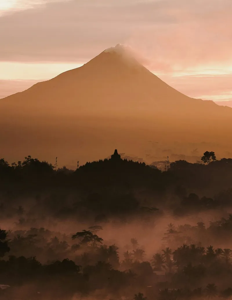 Borobudur Temple stupas glowing in warm sunset light over the Kedu Valley